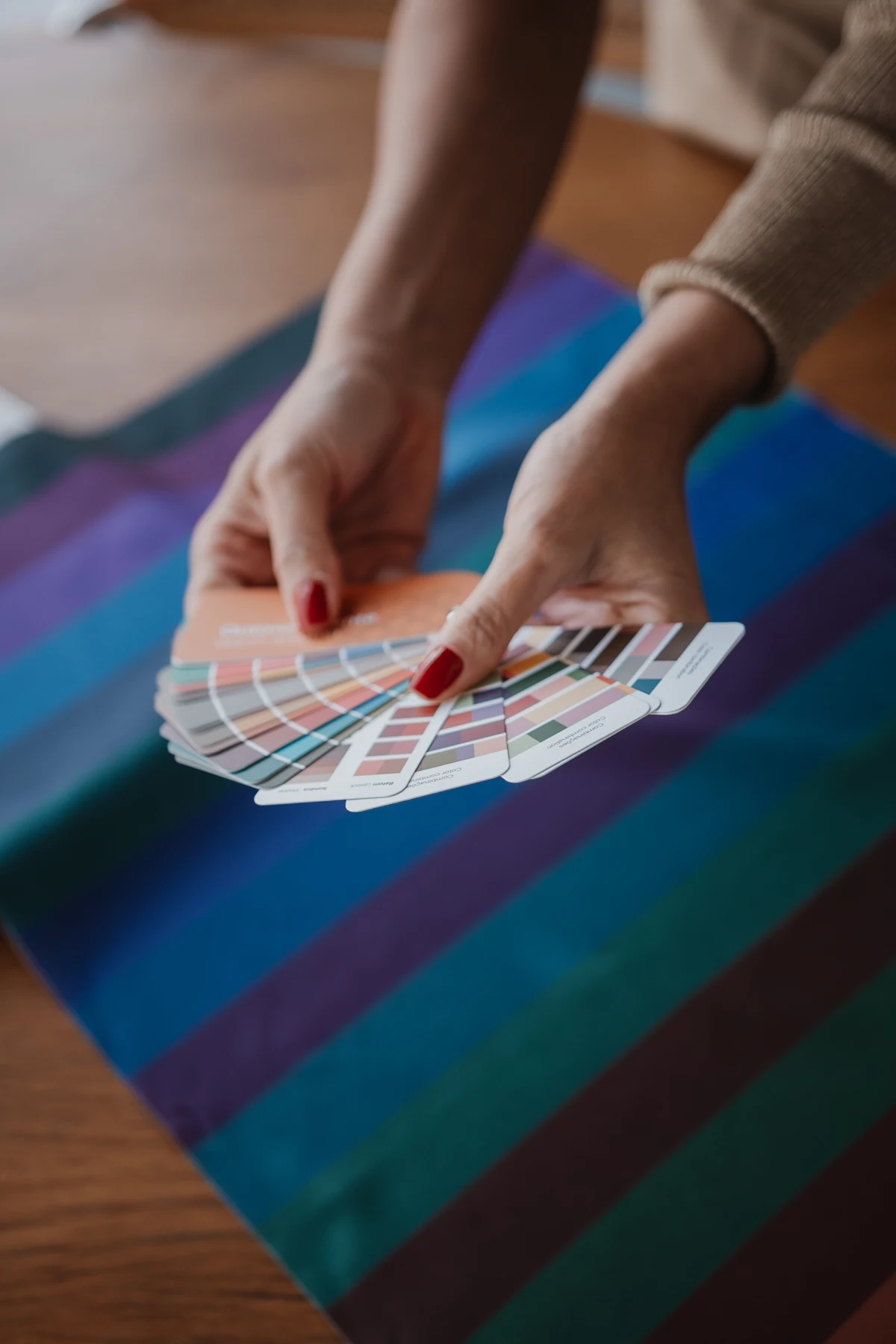 Mãos da consultora apresentando cartelas de coloração pessoal sobre tecidos coloridos